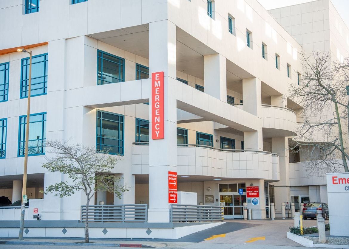 Exterior of modern hospital building with prominent emergency entrance and signage